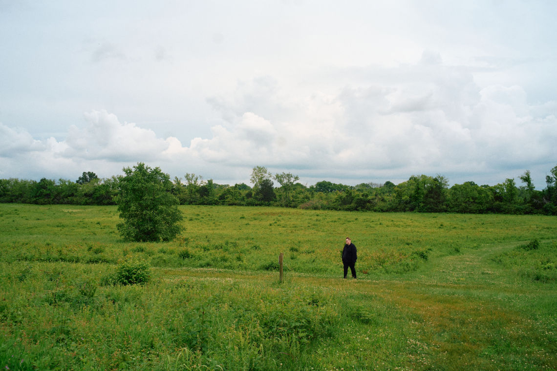 Jason standing in a field under a cloudy sky